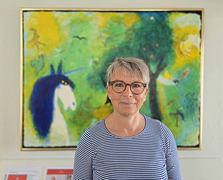 Mona Møberg Larsen foran farverigt maleri